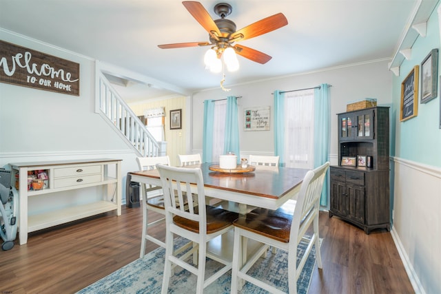 dining space with wood finished floors, baseboards, ceiling fan, stairs, and crown molding