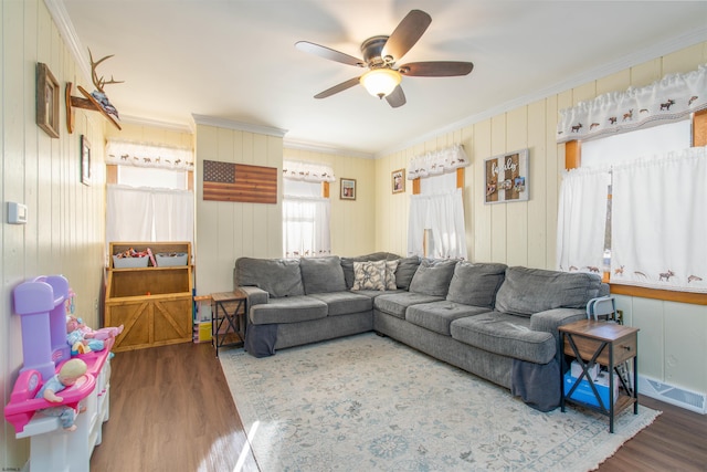 living area with crown molding, a ceiling fan, and wood finished floors