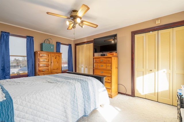 bedroom with light carpet, two closets, ornamental molding, and a ceiling fan