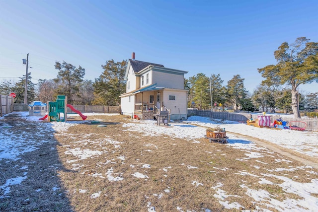 rear view of property with a chimney, a playground, and a fenced backyard