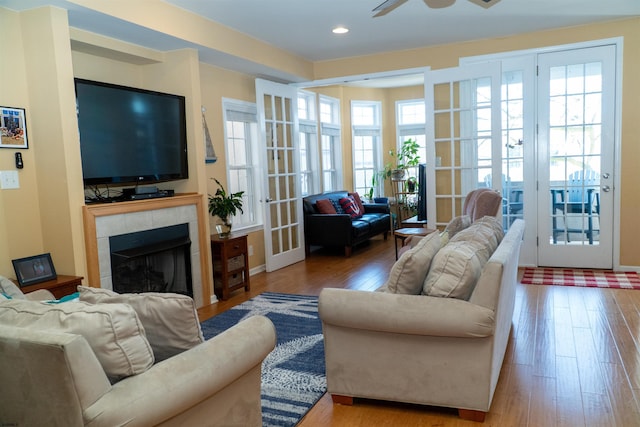 living room featuring a ceiling fan, hardwood / wood-style flooring, recessed lighting, french doors, and a tile fireplace