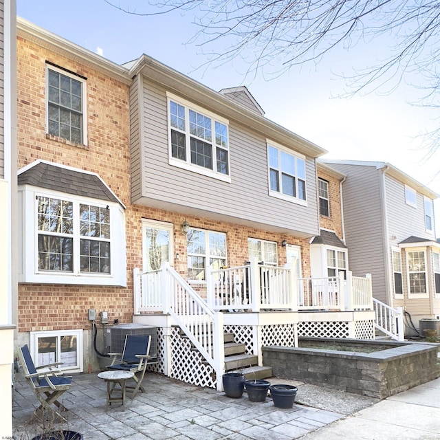 back of property with central air condition unit, a patio, and brick siding