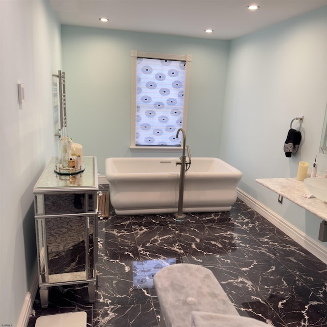 bathroom with marble finish floor, recessed lighting, baseboards, a freestanding bath, and vanity