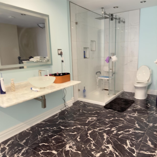 bathroom with toilet, marble finish floor, a stall shower, a sink, and baseboards