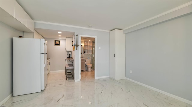 kitchen featuring marble finish floor, white cabinets, freestanding refrigerator, and baseboards