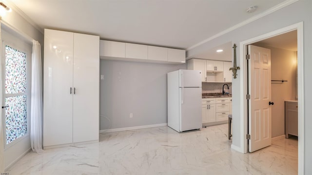 kitchen featuring marble finish floor, white cabinetry, freestanding refrigerator, and baseboards