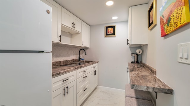 kitchen with baseboards, freestanding refrigerator, white cabinets, marble finish floor, and tasteful backsplash