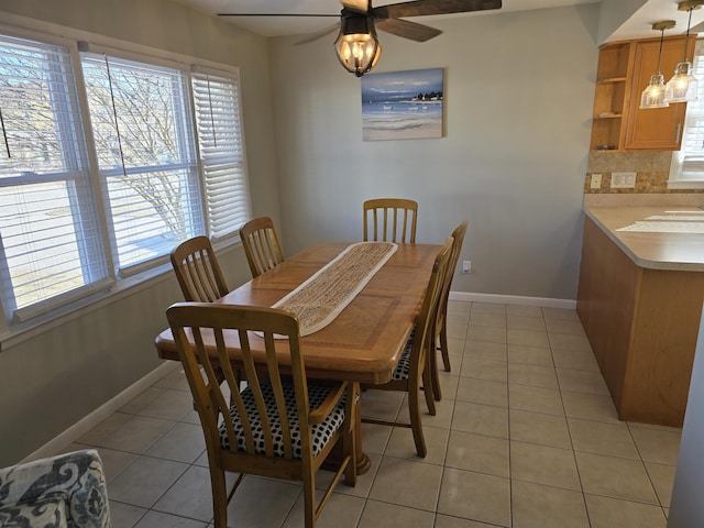 dining area with light tile patterned flooring, a ceiling fan, and baseboards