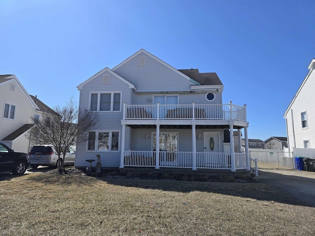 back of property featuring covered porch, a yard, and fence