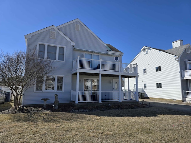 back of property with a yard, a balcony, and covered porch