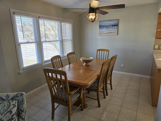 dining area with light tile patterned flooring, baseboards, and ceiling fan