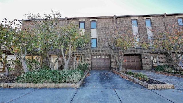 view of front of property with brick siding, an attached garage, and driveway