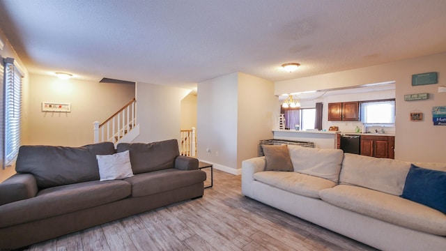 living area with light wood-type flooring, a textured ceiling, stairway, baseboards, and a chandelier