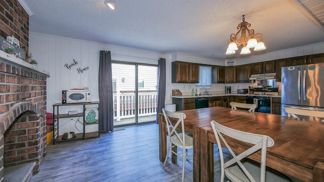 kitchen with gas stove, freestanding refrigerator, dark brown cabinets, under cabinet range hood, and dishwasher