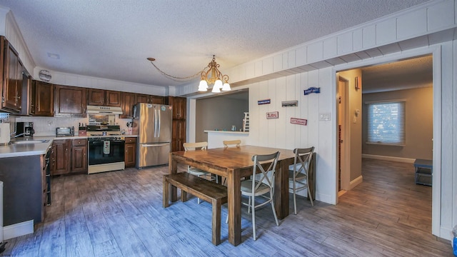 kitchen featuring hardwood / wood-style flooring, under cabinet range hood, range with gas stovetop, freestanding refrigerator, and light countertops