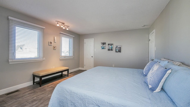 bedroom featuring visible vents, baseboards, and wood finished floors