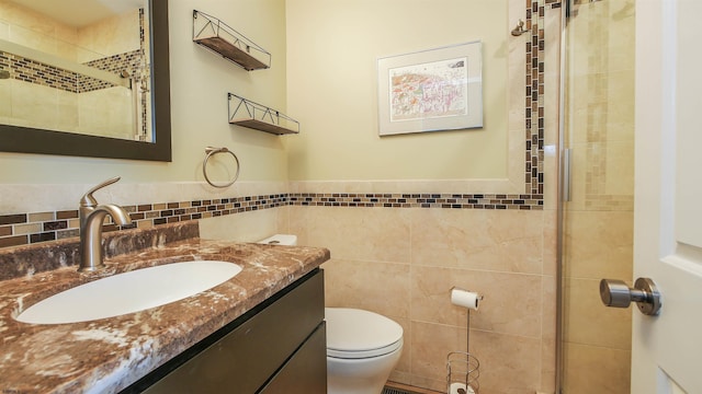 full bath with vanity, a wainscoted wall, tiled shower, tile walls, and toilet