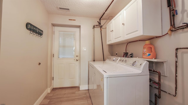 clothes washing area featuring visible vents, independent washer and dryer, a textured ceiling, cabinet space, and light wood finished floors