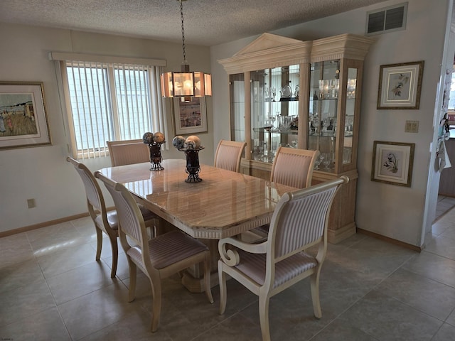 dining area with visible vents, baseboards, a textured ceiling, and light tile patterned flooring