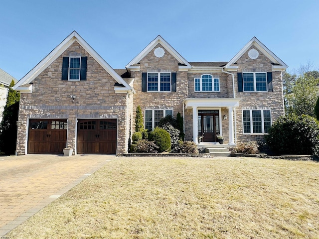 view of front of property with decorative driveway, an attached garage, and a front yard