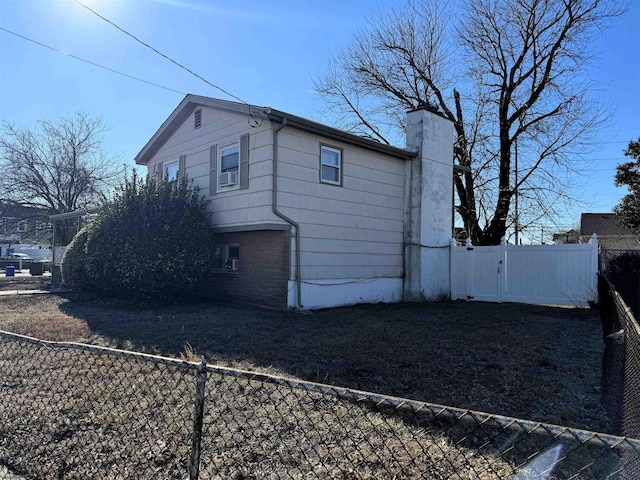 view of side of property with a fenced backyard, a chimney, and a gate