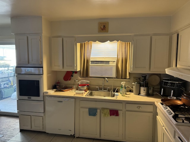 kitchen with a warming drawer, a sink, white appliances, white cabinets, and light countertops