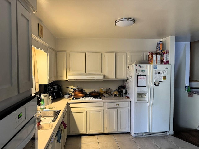 kitchen with under cabinet range hood, light tile patterned floors, white appliances, and light countertops