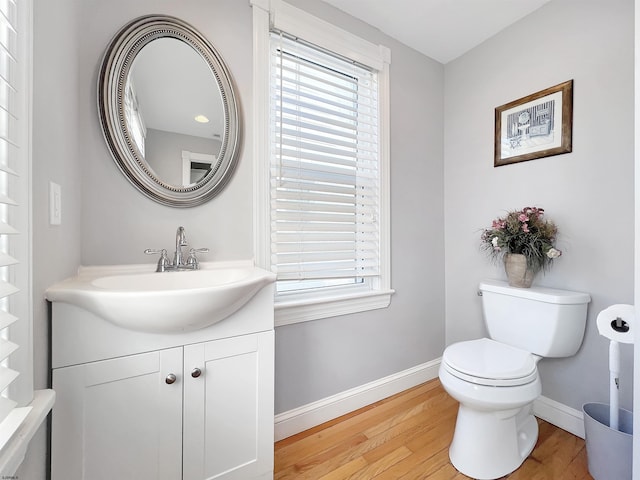 bathroom featuring toilet, wood finished floors, baseboards, and a healthy amount of sunlight