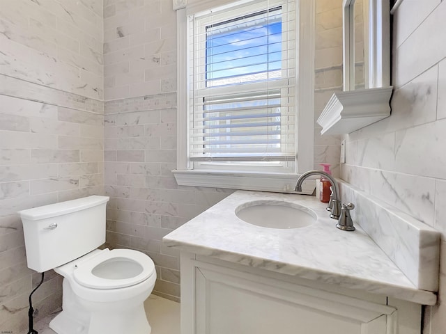 half bathroom with vanity, tile walls, and toilet