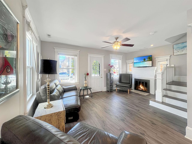 living room with visible vents, a fireplace with flush hearth, wood finished floors, baseboards, and ceiling fan