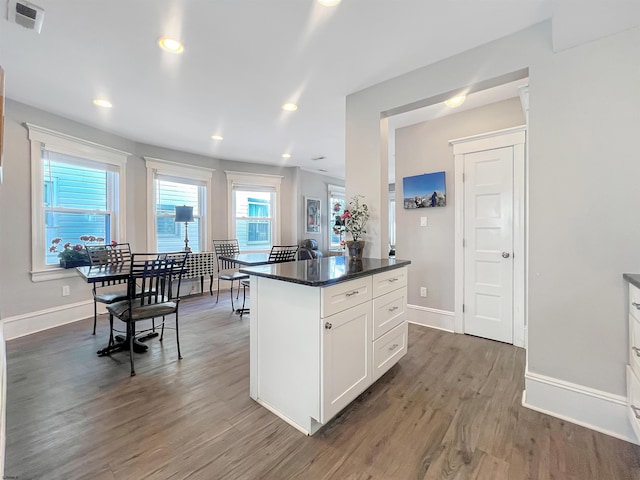 kitchen featuring visible vents, dark countertops, wood finished floors, white cabinetry, and baseboards