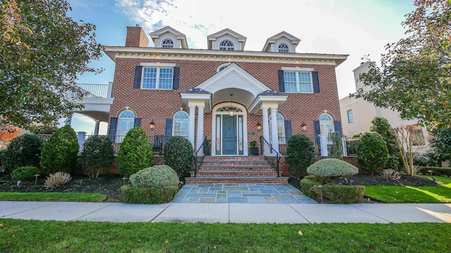 colonial house featuring a balcony and brick siding