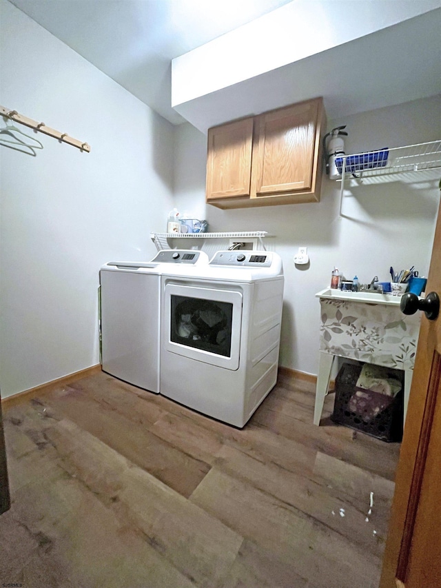 washroom featuring washer and dryer, cabinet space, light wood-type flooring, and baseboards