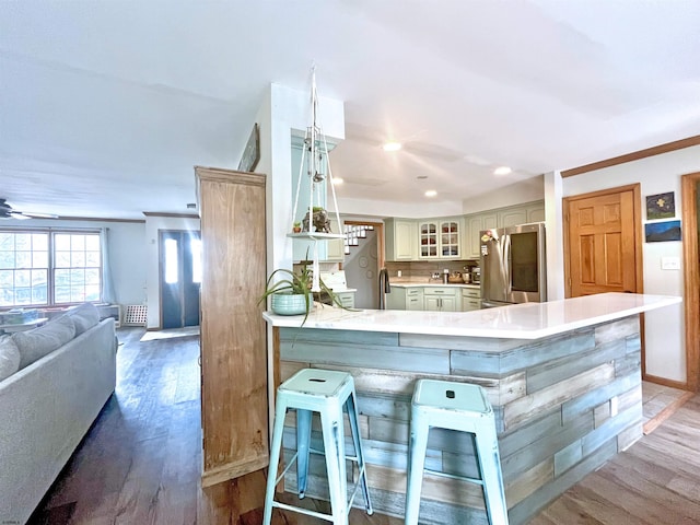 kitchen with glass insert cabinets, a peninsula, wood finished floors, and smart refrigerator