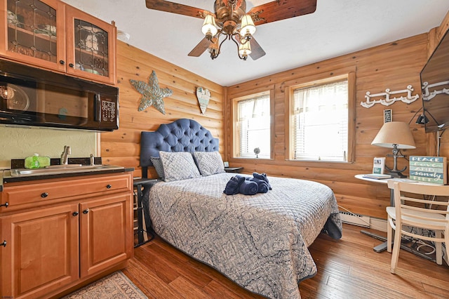 bedroom with a sink, log walls, wood-type flooring, and ceiling fan