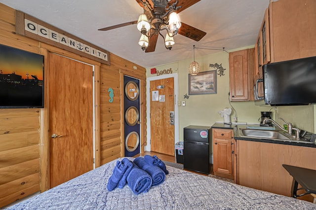 kitchen with brown cabinets, a sink, dark countertops, freestanding refrigerator, and ceiling fan