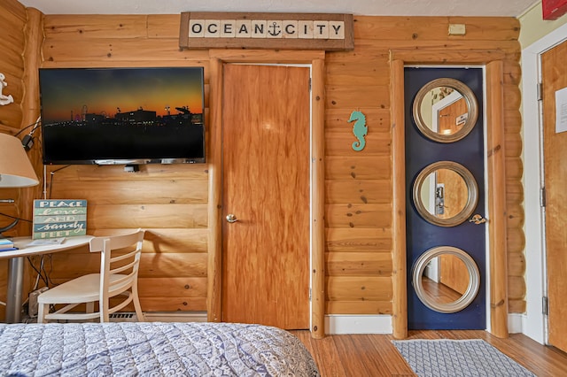 bedroom with log walls and wood finished floors