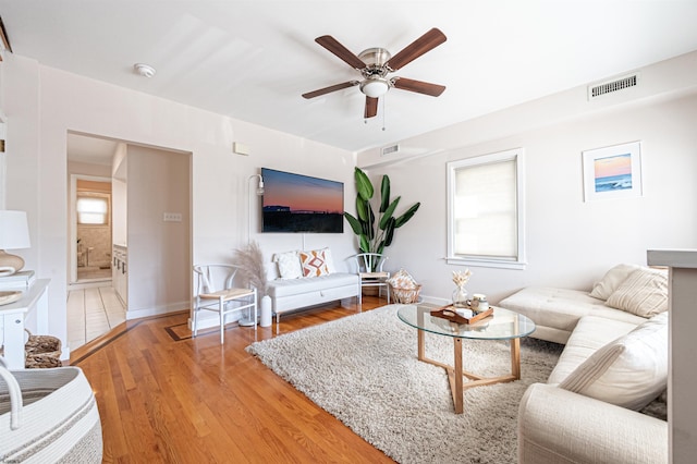 living area with a ceiling fan, light wood-style floors, visible vents, and a healthy amount of sunlight