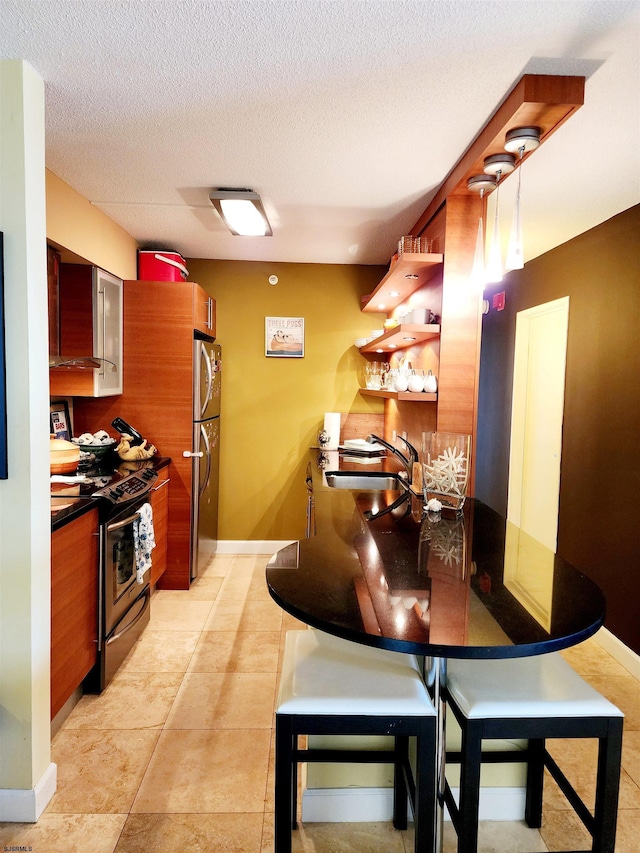 kitchen featuring light tile patterned flooring, freestanding refrigerator, a sink, electric stove, and a textured ceiling