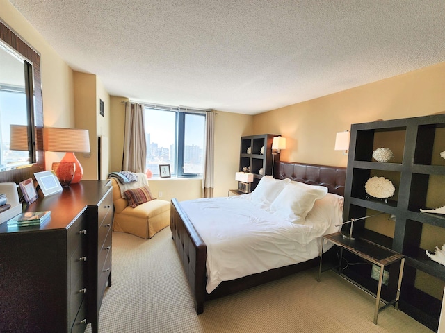 bedroom with multiple windows, light colored carpet, and a textured ceiling