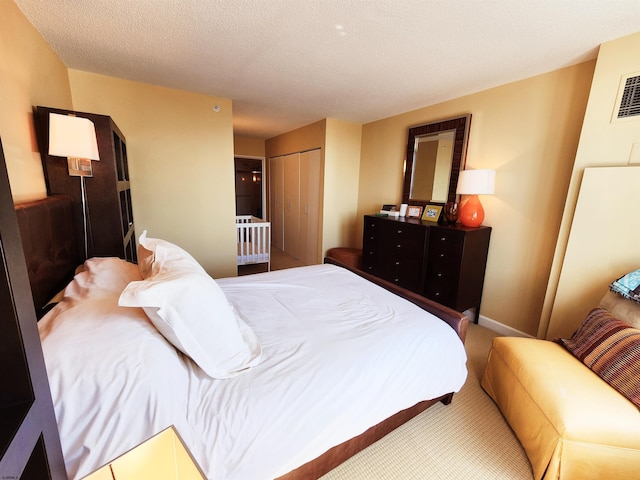 bedroom featuring visible vents, baseboards, a closet, a textured ceiling, and carpet flooring