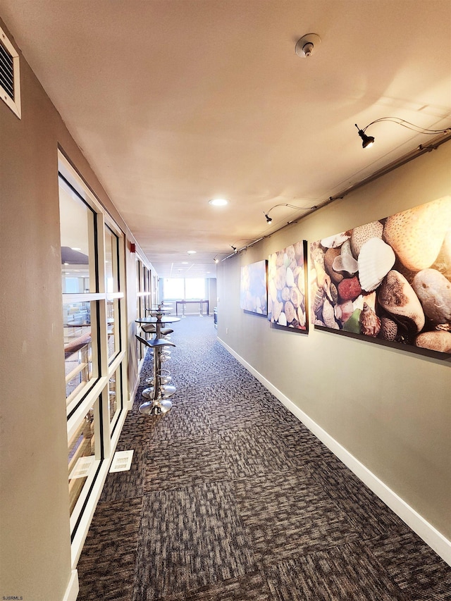 corridor featuring carpet flooring, visible vents, and baseboards