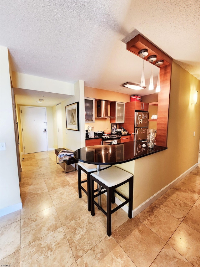 kitchen with electric stove, a textured ceiling, dark countertops, fridge, and a peninsula