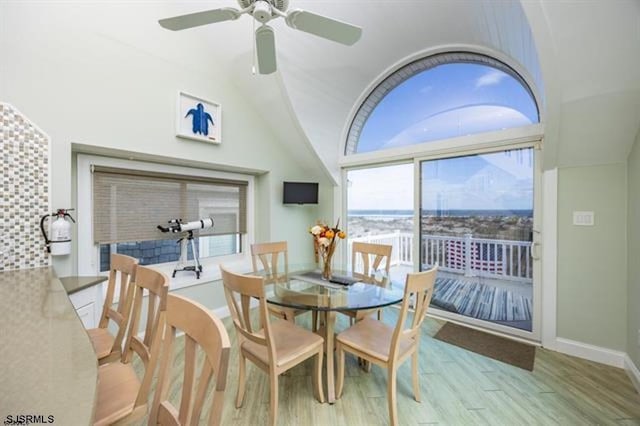 dining area featuring vaulted ceiling, ceiling fan, baseboards, and wood finished floors