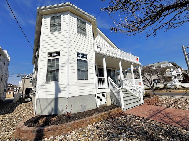 view of front of home with crawl space, a porch, and a balcony