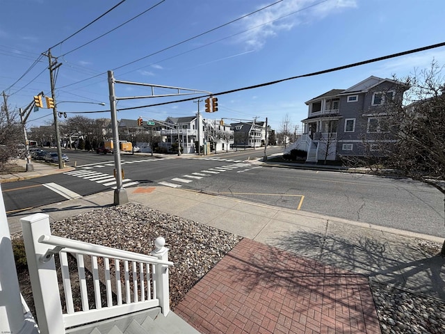 view of road with sidewalks, a residential view, curbs, and traffic lights