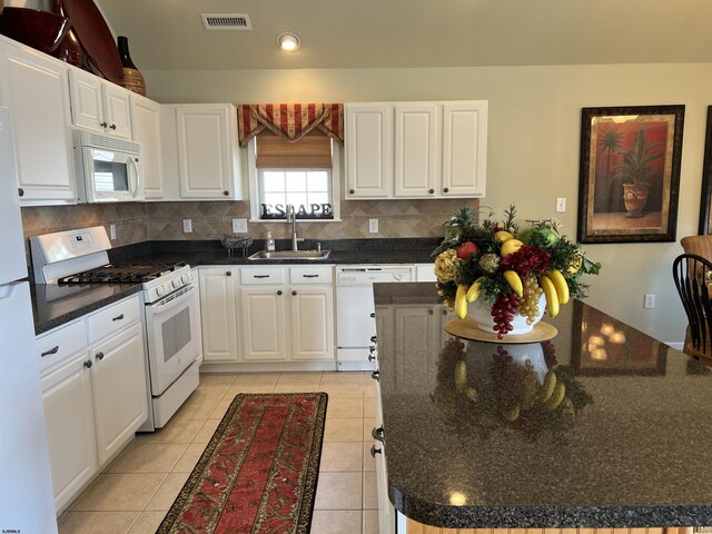 kitchen featuring white appliances, visible vents, a sink, white cabinetry, and tasteful backsplash