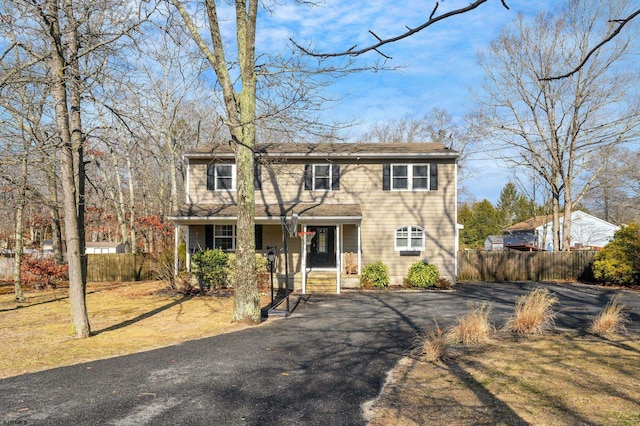 view of front of property with covered porch, driveway, and fence