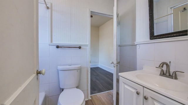 bathroom featuring tile walls, toilet, vanity, and wood finished floors