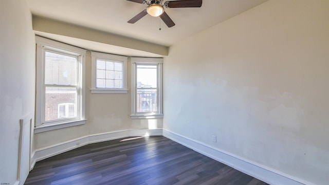 empty room featuring ceiling fan, baseboards, and dark wood finished floors